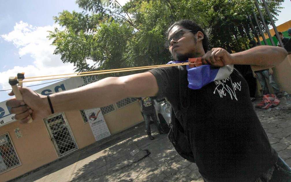 Um rapaz usa um estilingue contra policiais em Manágua (Foto: Inti Ocon / AFP Photo)