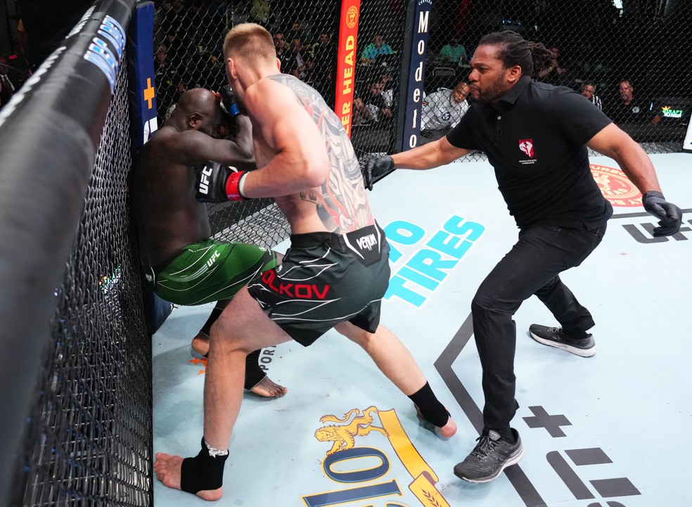 Alexander Volkov (centro) acerta sequência de golpes em Jairzinho Rozenstruik (esq.), e Herb Dean (dir.) se move para encerrar a luta — Foto: Chris Unger/Zuffa LLC