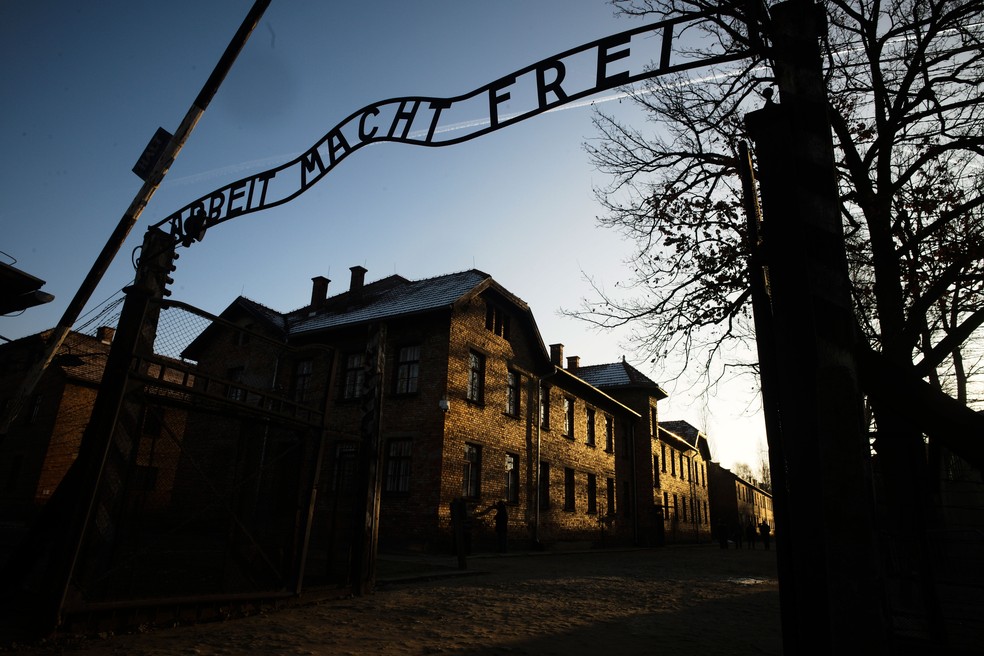 Sol ilumina prédios atrás da entrada do antigo campo de extermínio nazista de Auschwitz-Birkenau em Oswiecim, na Polônia, nesta sexta-feira (6)  — Foto: Markus Schreiber/AP