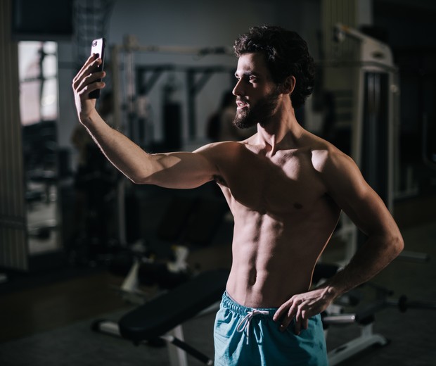 Homem tira uma selfie sem camisa na academia (Foto: Getty Images)