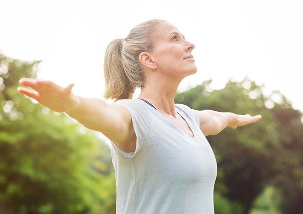 Mature woman doing yoga at park and looking away. Senior blonde woman enjoying nature during a breathing exercise. Portrait of a fitness woman stretching arms and looking away outdoor. "r (Foto: Getty Images/iStockphoto)
