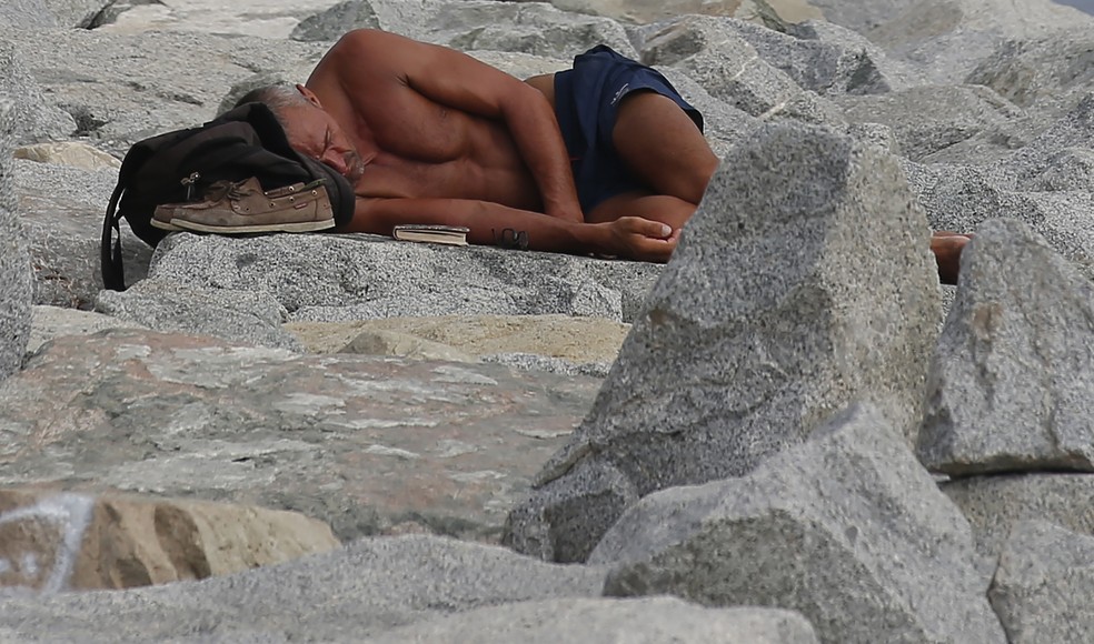 Homem dorme perto de praia em dia de verão em Barcelona, na Espanha (Foto: AP Photo/Manu Fernandez)