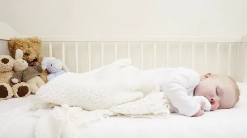 Foto acima mostra bebê em posição de maior risco para a síndrome da morte súbita: crianças pequenas não devem dormir de barriga para baixo, e berços devem ficar livres de almofadas e bichinhos (Foto: GETTY IMAGES via BBC)