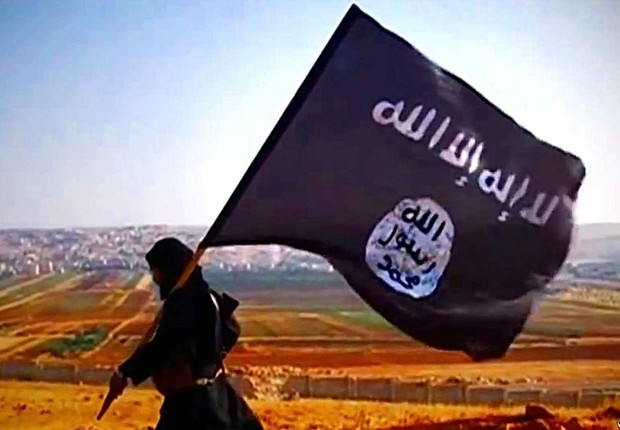 Militante carrega bandeira do Estado Islâmico (EI) : grupo coordena e lança ações terroristas (Foto: Reprodução/YouTube)