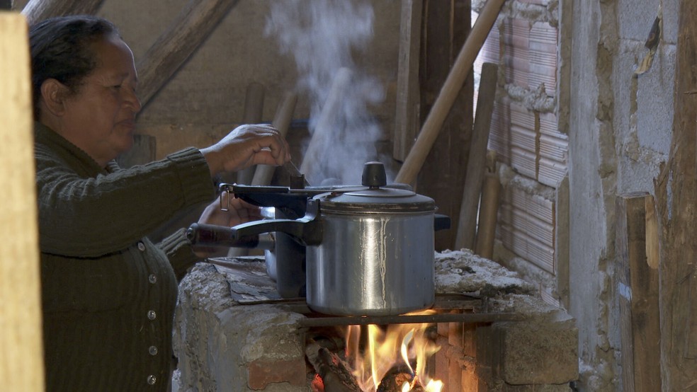 Dona Cida cozinhando em fogão a lenha improvisado na Zona Sul de SP — Foto: Reprodução/TV Globo