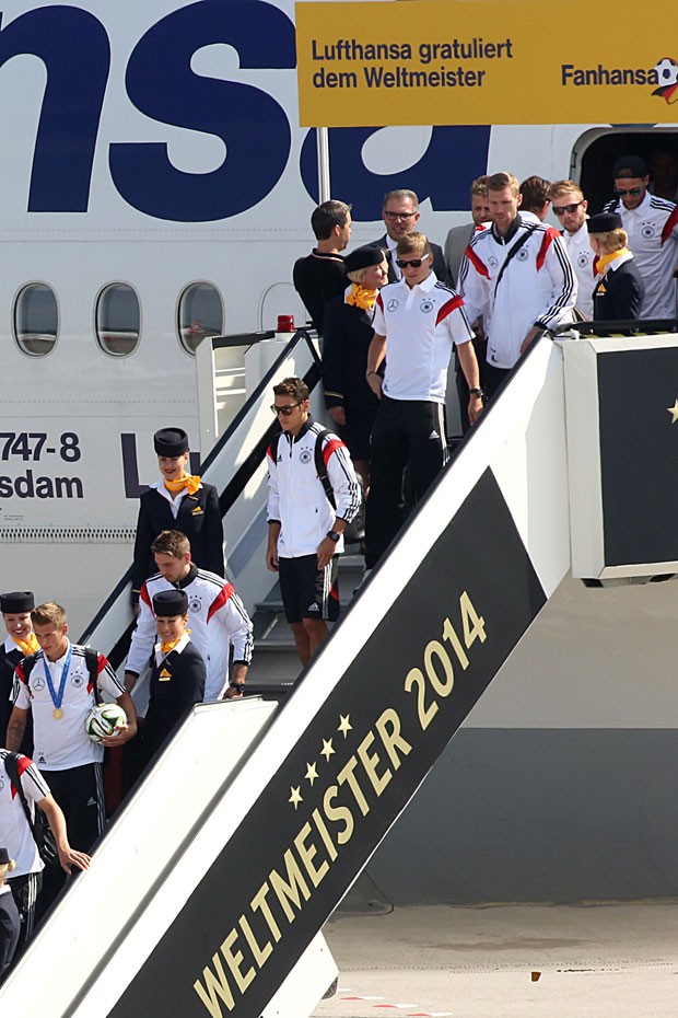 Jogadores descem de avião ao desembarcarem no aeroporto de Tegel, em Berlim, nesta terça-feira (15) (Foto: Adam Berry/AFP)