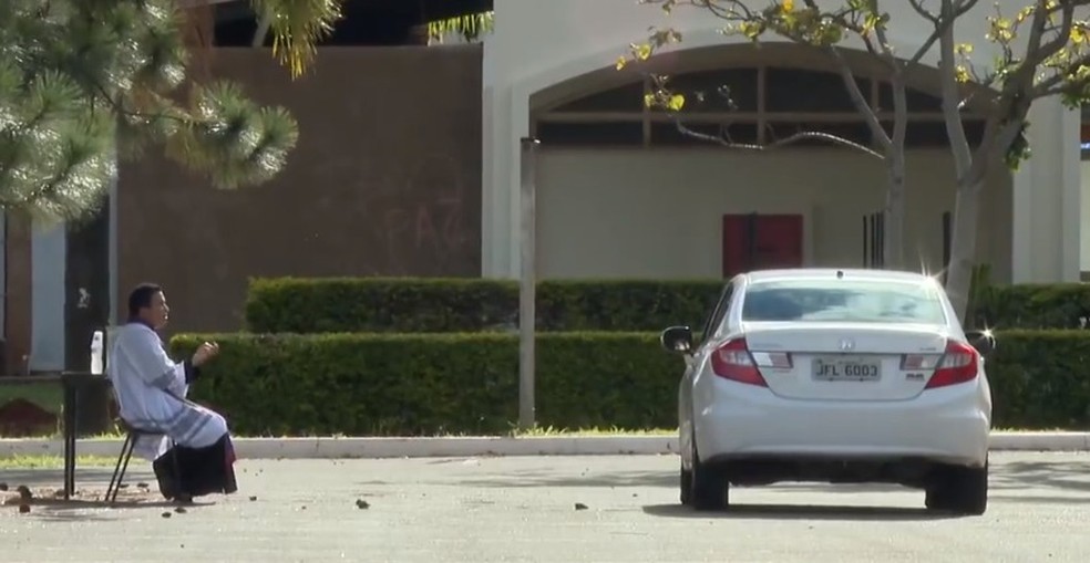 Padre recebendo fiéis por meio de atendimento drive-thru no DF — Foto: TV Globo/Reprodução 