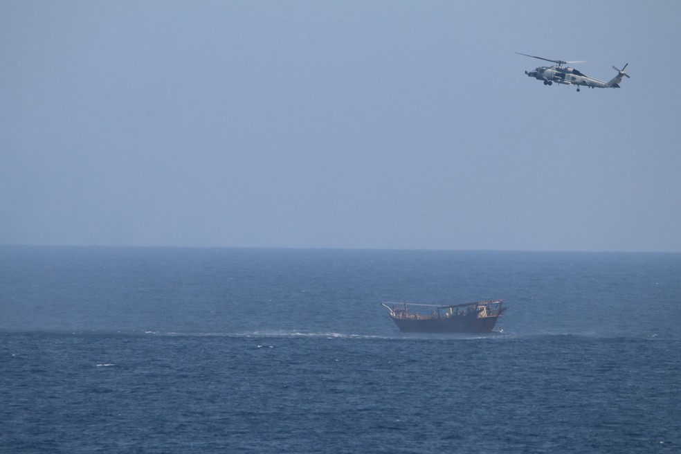 Helicóptero SH-60 Seahawk voa acima da embarcação que levava carregamento de armas apreendidas no Mar da Arábia — Foto: Marinha dos EUA via Reuters
