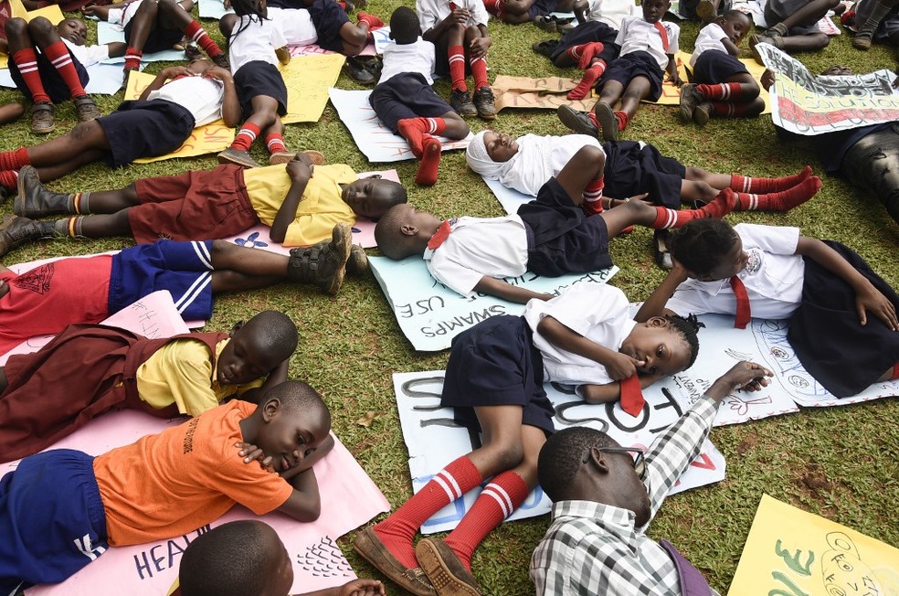 Crianças descansam sobre cartazes de protesto pelo clima em Wakiso, Uganda. — Foto: Isaac Kasamani/AFP