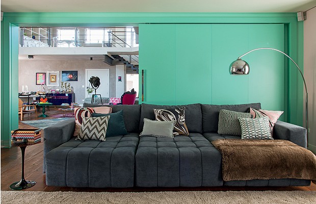 Home theater: O sofá, da Veneza, possui almofadas feitas de lenços Pucci. Formica turquesa reveste aporta divisória, ao fundo, que separa o living (Foto: Cacá Bratke)
