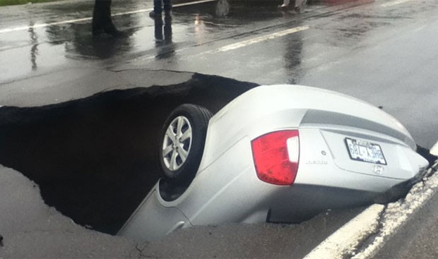 Carro foi engolido por um buraco que se formou em uma estrada em Ottawa. (Foto: Reprodução)