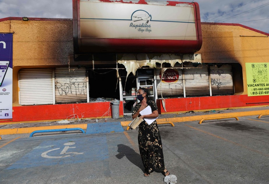 Uma mulher fica em frente ao prédio onde criminosos incendiaram lojas, em Ciudad Juarez, estado de Chihuahua, México