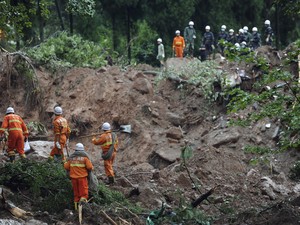 Bombeiros trabalham para socorrer pessoas soterradas após deslizamento de terra na província de  Sichuan, no Sudoeste da China. Ao menos 18 pessoas morreram. Cinco estão desaparecidas (Foto: AP Photo)
