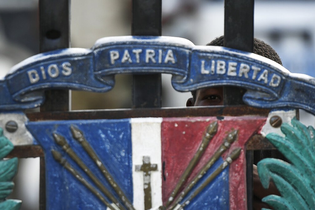 Garoto olha em portão fechado na fronteira entre Haiti e República Dominicana nesta quinta-feira (8) após o governo dominicano fechar a fronteira em sequência à morte de Jovenel Moise, presidente haitiano — Foto: Matias Delacroix/AP Photo