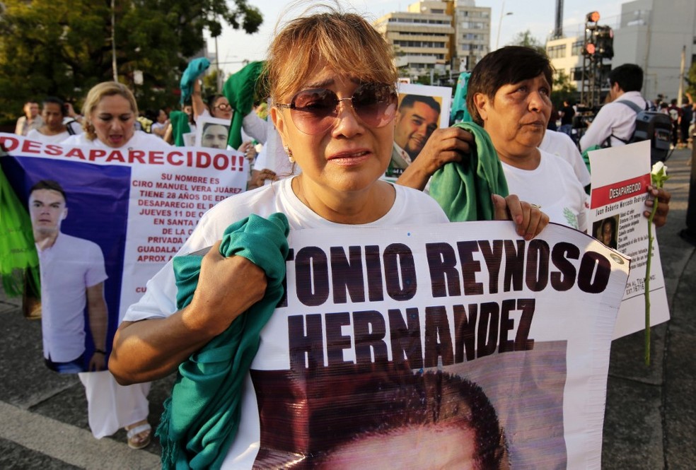 Mulher segura cartaz com foto de desaparecido em protesto na cidade de Guadalajara, México, na sexta (30).  — Foto: Ulises Ruiz/AFP