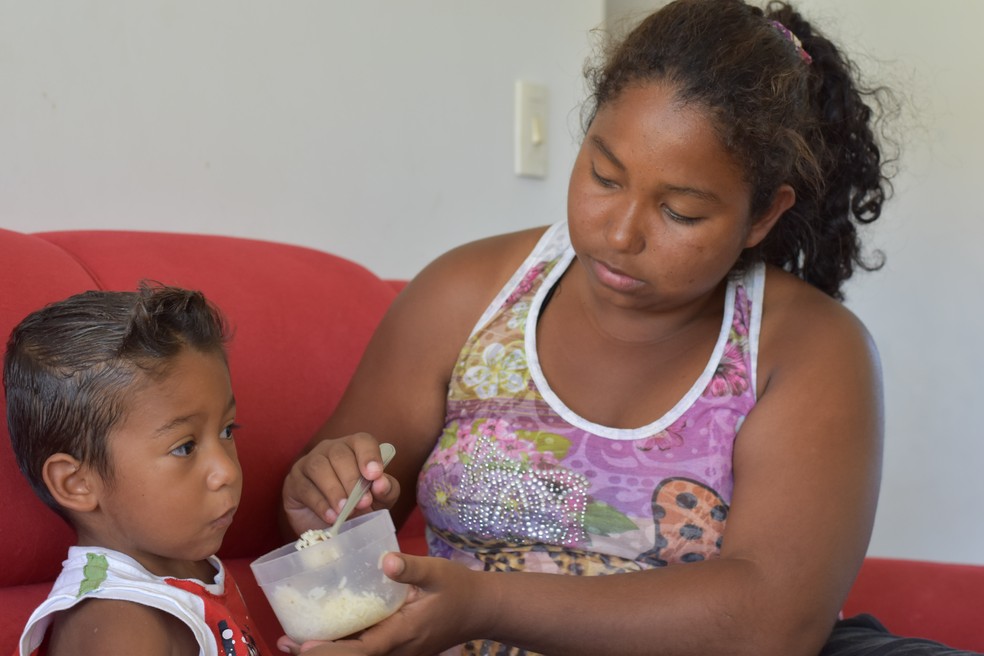 Venezuelana Andrea Villalba oferece arroz ao filho em abrigo de Porto Alegre â€” Foto: Joyce Heurich/G1