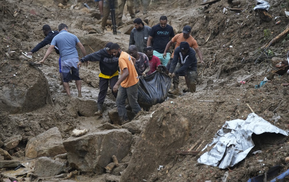 Moradores e voluntários retiram o corpo de uma vítima dos deslizamentos em Petrópolis (RJ) nesta quarta (16)  — Foto: Silvia Izquierdo/AP