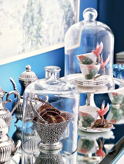 Na mesa do café, as xícaras chinesas com araras nas asas, arrematadas em leilão da coleção de Bethy Lagardère, ganham status de arte sob redomas de vidro. Na cesta de prata, biscoitinhos