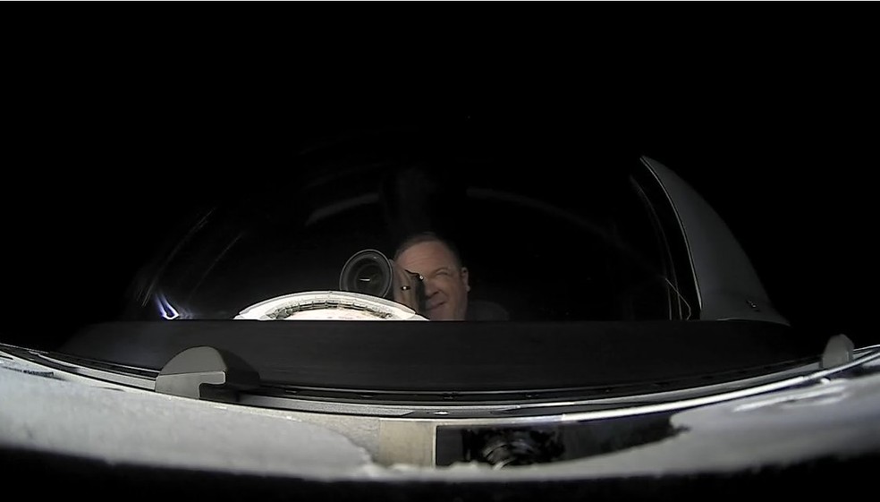 Chris Sembroski, tripulante da missão Inspiration4 fotografando a Terra através do domo da cápsula da SpaceX — Foto: Redes sociais/Inspiration4