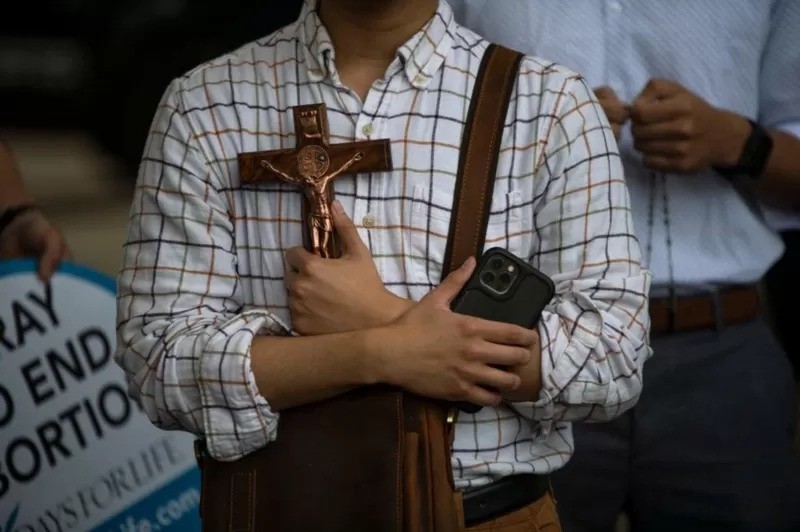 Ativista antiaborto segura crucifixo em frente a manifestantesdo lado de fora da prefeitura em Houston, Texas (Foto: Getty Images via BBC News)