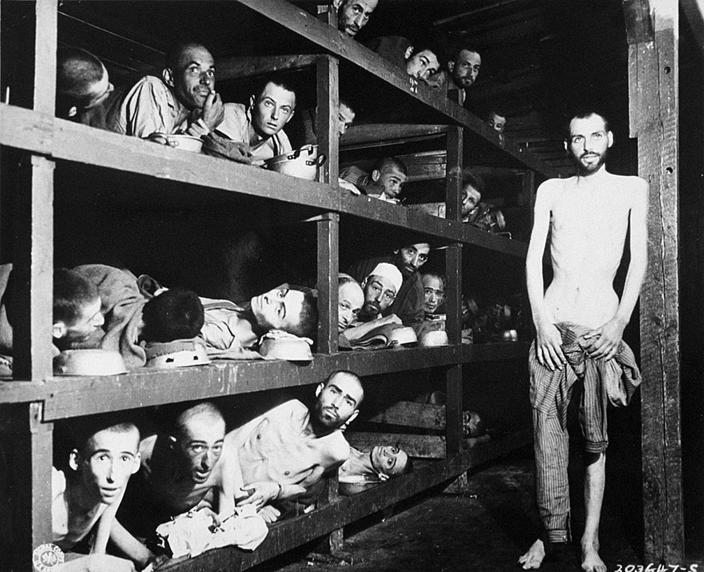 Trabalhadores escravizados em seus leitos no campo de concentração após a libertação em abril de 1945. Na foto, está Elie Wiesel, futuro vencedor do Nobel da Paz, sétimo a partir esquerda, na segunda fileira de beliches, junto à viga de madeira — Foto: Getty Images via BBC