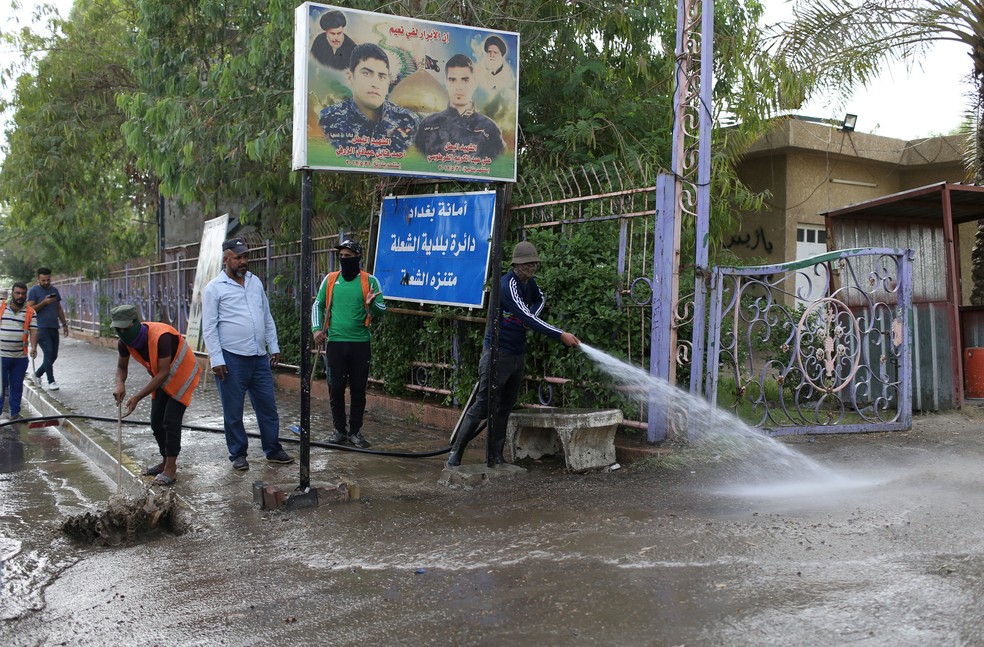 Trabalhadores limpam local de atentado suicida no norte de BagdÃ¡, nesta quinta-feira (24)  (Foto: Thaier Al-Sudani/ Reuters)