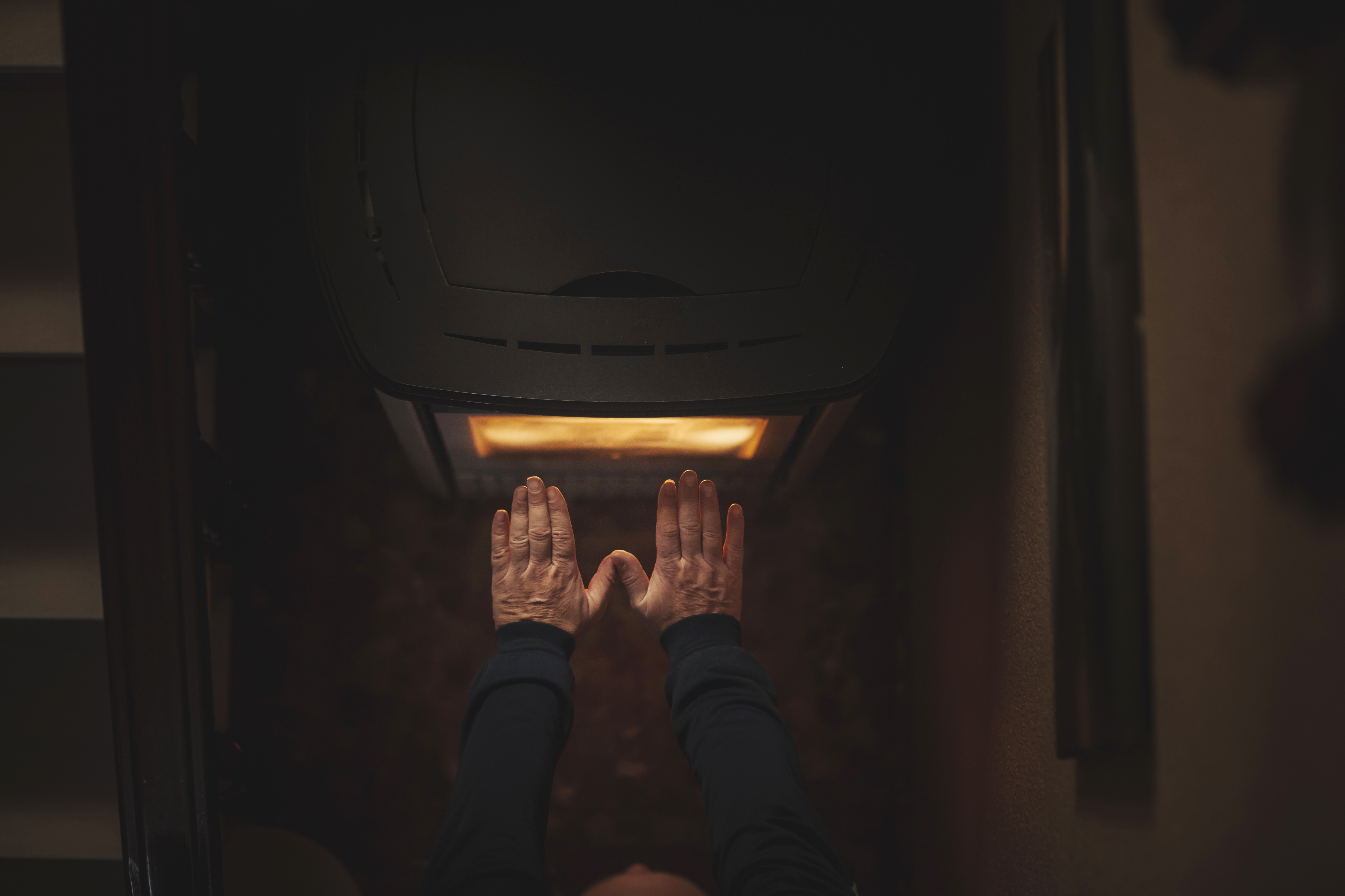 man's hands warming up on an electric stove. (Foto: Getty Images)
