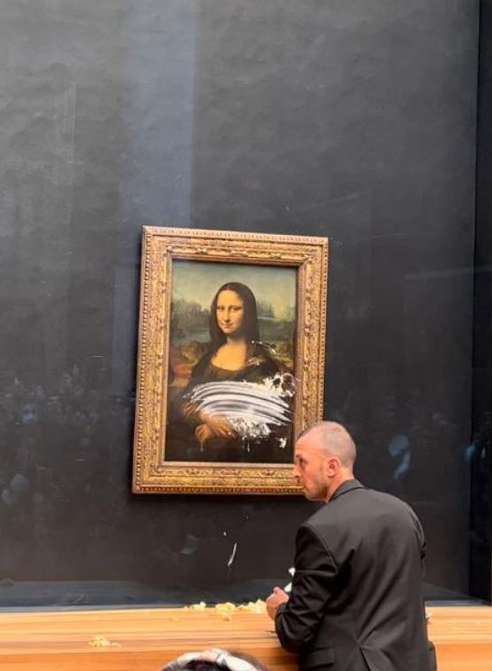 Funcionário do Louvre tenta retirar mancha após ataque ao quadro, em 29 de maio de 2022.  — Foto: Reprodução
