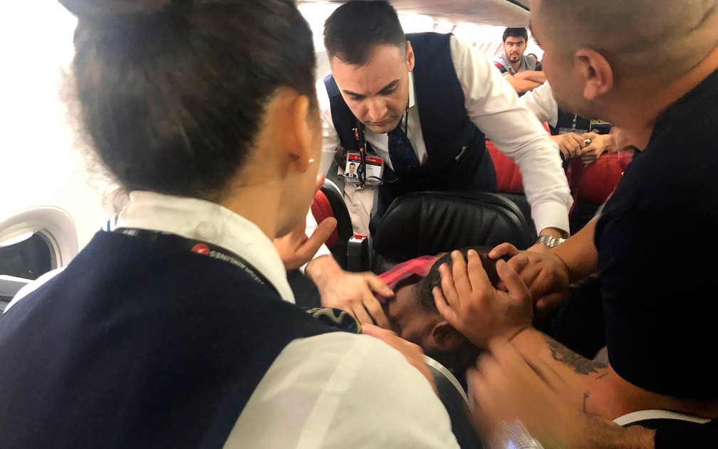 Passageiros e comissários de bordo de um voo da Turkish Airlines tentam conter homem que gritava e tentava quebrar janela durante voo de Istambul a Cartum, na sexta-feira (14) — Foto: AP Photo/Hussein Malla