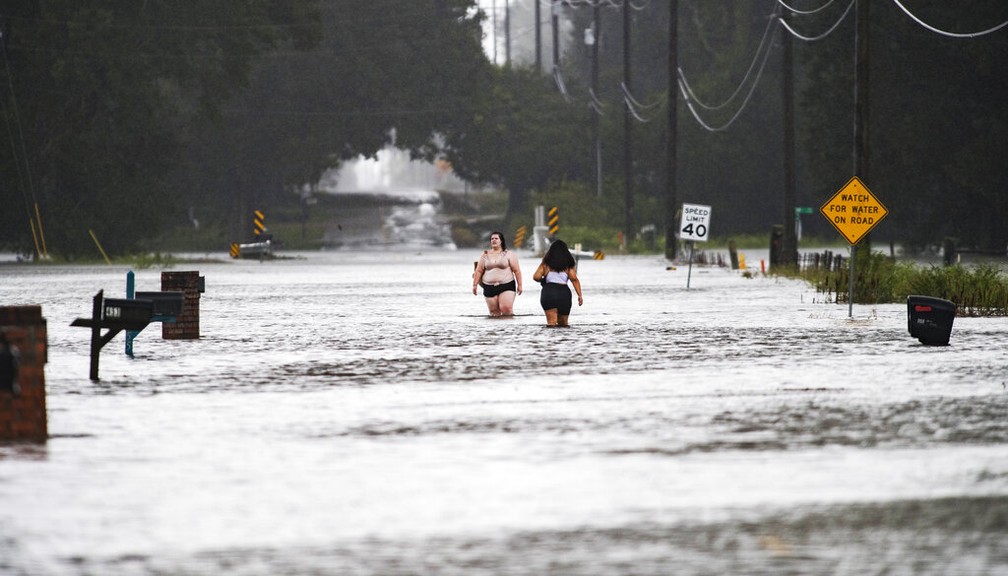 Moradores de Lafayette, na Louisiana (EUA), atravessam rua alagada após passagem do furacão Laura nesta quinta-feira (27) — Foto: Leslie Westbrook/The Advocate via AP