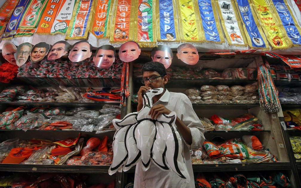 Homem assopra um logo inflável do partido Bharatiya Janata (BJP) em loja de Mumbai com artigos de diversos partidos políticos, na Índia, na quarta-feira (10) — Foto: Reuters/Francis Mascarenhas