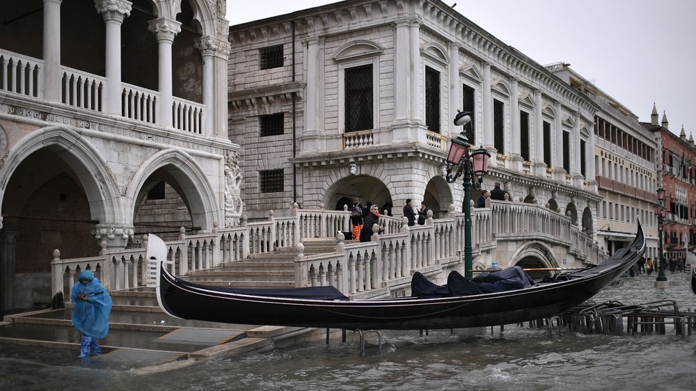 Turistas usam uma passarela improvisada para deixar hotel em Veneza
