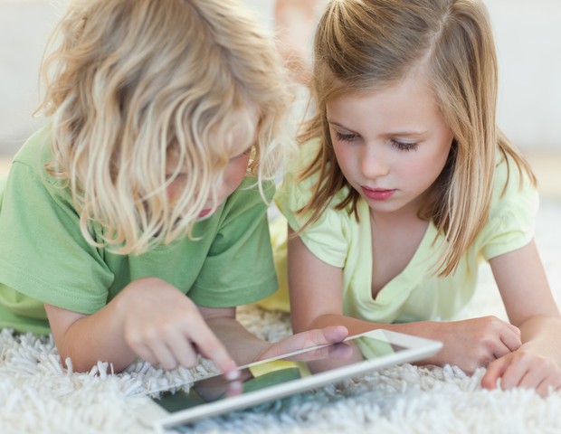 Crianças brincando com iPad no chão (Foto: Shutterstock)