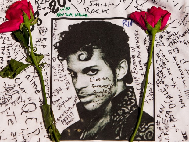 Flores são colocadas sobre uma camisa com mensagens escritas por fãs do cantor Prince em um memorial criado do lado de fora do Apollo Theater em Nova York, nos EUA. Prince foi encontrado morto na quinta-feira (21) com 57 anos (Foto: Andres Kudacki/AP)
