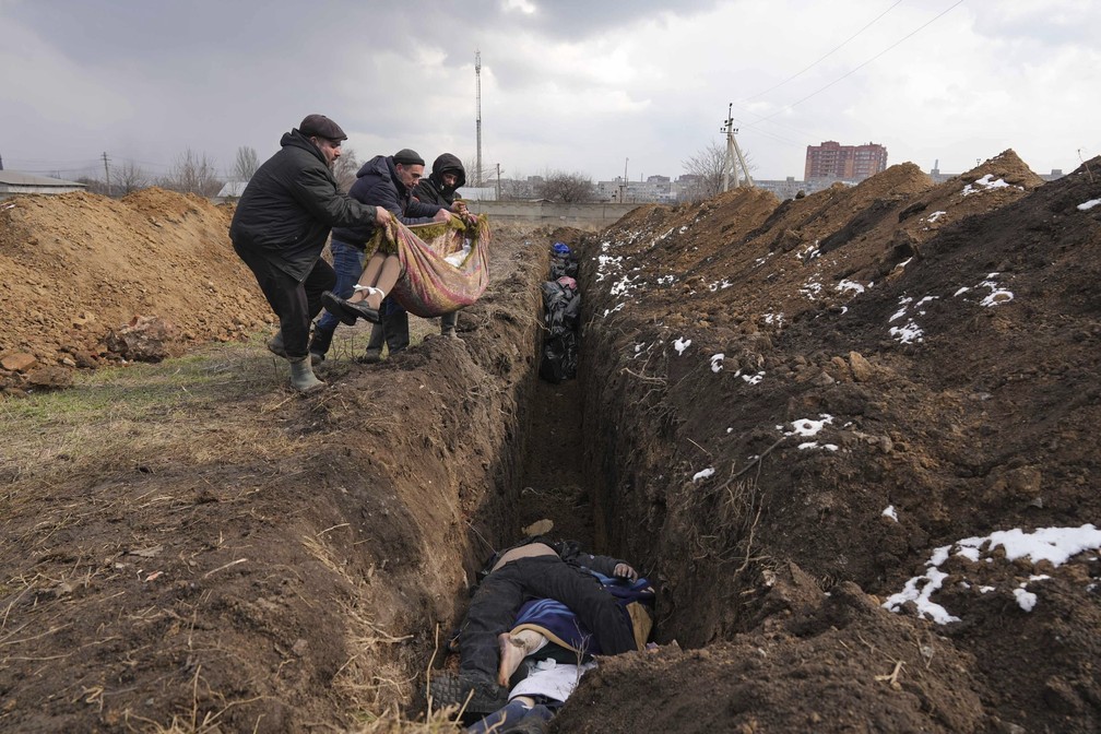 9 de maro - Corpos so jogados em uma vala comum nos arredores de Mariupol, na Ucrnia. Bombardeios russos impediam a realizao de enterros — Foto: Evgeniy Maloletka/AP