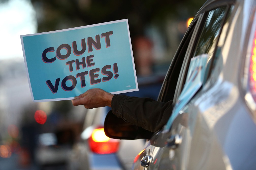Motorista segura placa com a frase 'Contem os votos!' perto da Casa Branca, em Washington, nesta quinta-feira (5) — Foto: Hannah McKay/Reuters