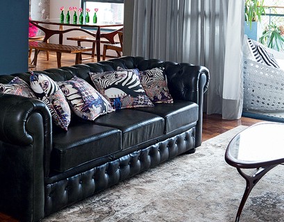 O tecido de zebra comprado em Berlim virou almofadas que animam o sofá preto de Camila Salek. Solução simples, que faz muita diferença