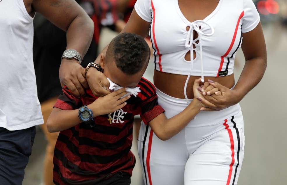 Criança usa lenço nos olhos após policiais jogarem bombas de gás no final do desfile do Flamengo no Rio de Janeiro neste domingo (24) — Foto: Ueslei Marcelino/Reuters