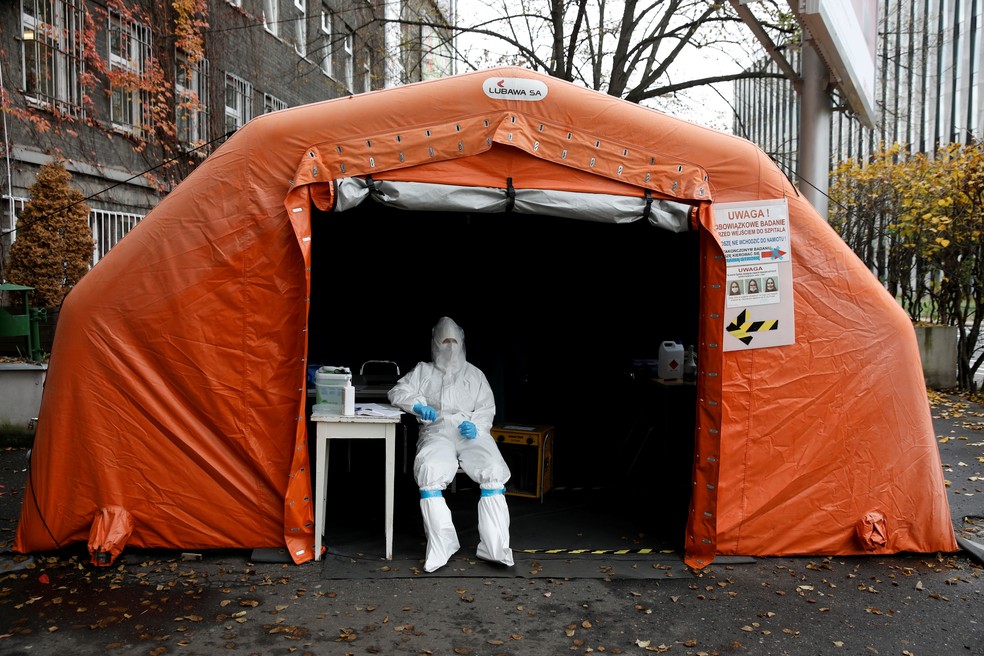 Profissional de saúde usando roupa protetora aguarda pessoas para serem testadas em um centro de testagem dentro de uma barraca em frente a um hospital em Varsóvia, na Polônia, no dia 27 de outubro. — Foto: Kacper Pempel/Reuters