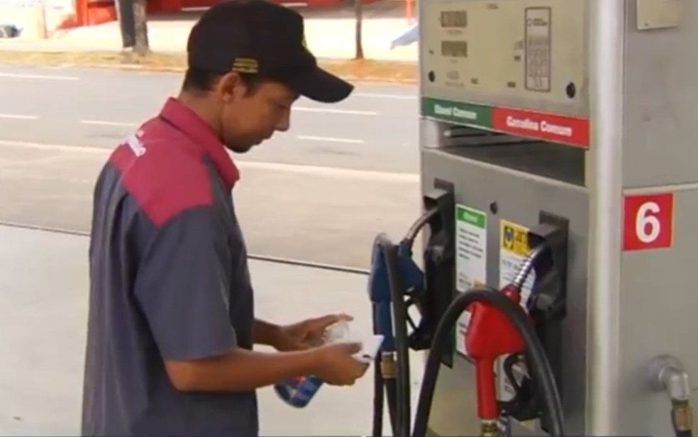 Frentista faz higienização com álcool gel em posto de combustíveis em Goiânia, Goiás — Foto: Reprodução/TV Anhanguera