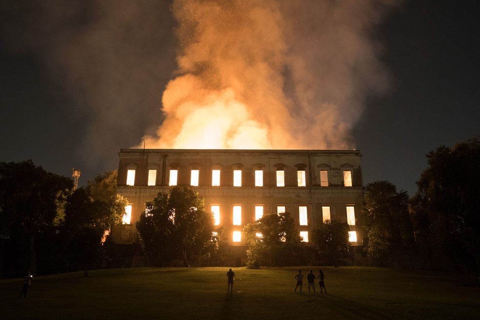 Pessoas observam o incêndio no Museu Nacional, no Rio de Janeiro, na noite de domingo (2) (Foto: Leo Correa/AP)