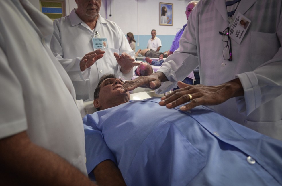 Voluntários preparam médium João Berbel para cirurgias espirituais no Instituto de Medicina do Além, em Franca (SP) (Foto: Rodolfo Tiengo/G1)