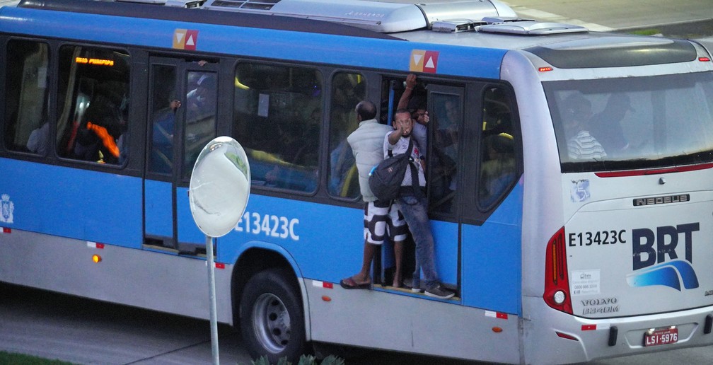 Passageiros andam do lado de fora do BRT lotado — Foto: Marcos Serra Lima/G1