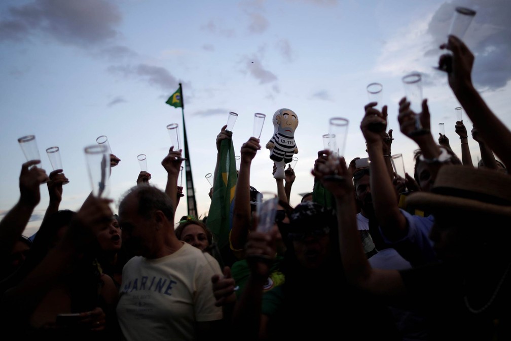 Manifestantes contrários a Lula erguem taças e um 'pixuleco' enquanto brindam com champanhe comemorando a condenação do ex-presidente na Praça dos Três Poderes, em Brasília (Foto: Ueslei Marcelino/Reuters)