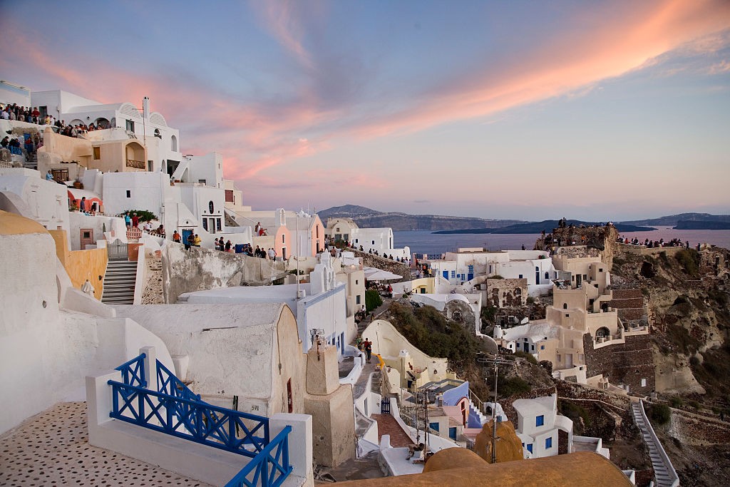 Tourists watching the sunset in Oia, pronounced 'Ia', it is the most famous of all villages of Santorini. It is world known for its quite life and fantastic sunset and it is obviously the most beautiful and picturesque village of Santorini. (Photo by In P (Foto: Corbis via Getty Images)