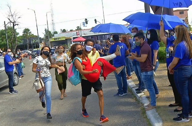 Candidata de vestibular com perna enfaixada é carregada nos braços até a entrada para não se atrasar para a prova, em Fortaleza