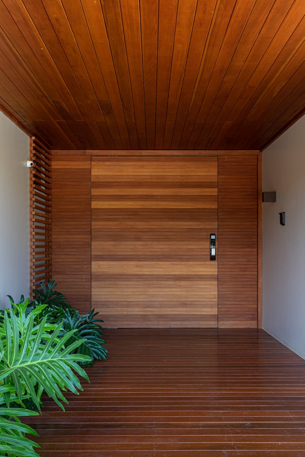 A aconchegante entrada da casa tem enorme porta de madeira, e também foro e piso do mesmo material 