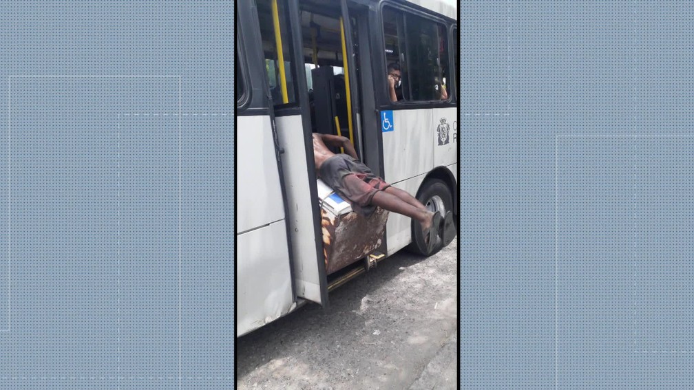 Homem salta e tenta passar por cima de geladeira colocada na porta de trás de ônibus no Rio — Foto: Reprodução/ TV Globo