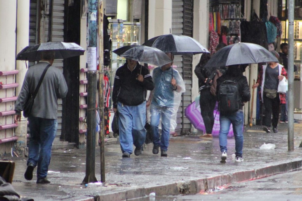 Pedestres se protegem da chuva no Centro de São Paulo (SP), na manhã desta quinta-feira (4) — Foto: Willian Moreira/Futura Press/Estadão Conteúdo