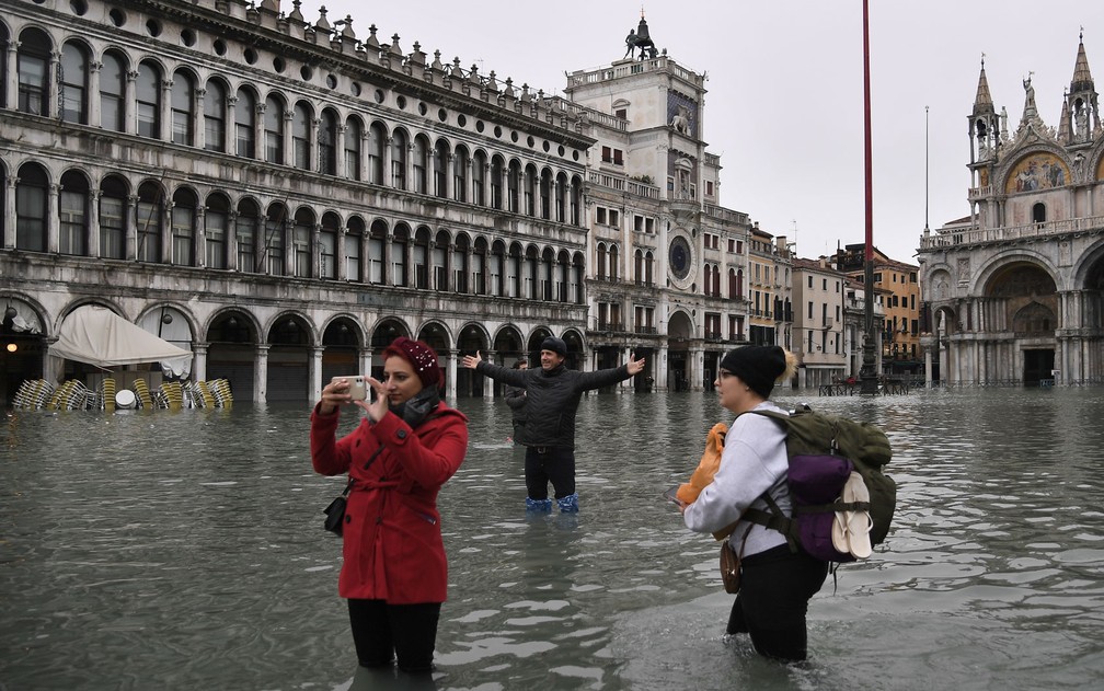 Turistas atravessam a praça inundada de São Marcos — Foto: Marco Bertorello / AFP Photo